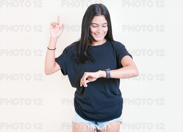 Smiling teen girl looking at hand watch isolated. Happy young woman looking at hand watch isolated