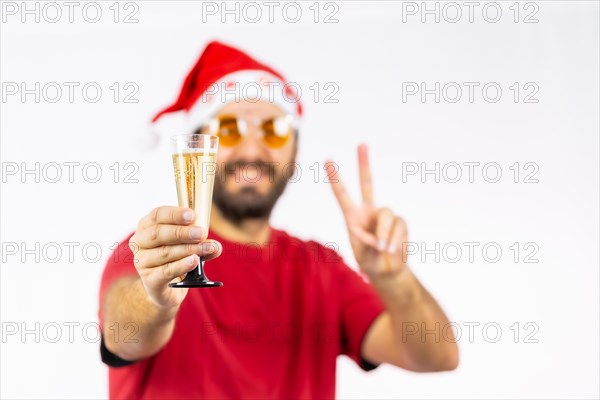 Very happy young Caucasian man with red Christmas hat toasting with a glass of champagne on a white background