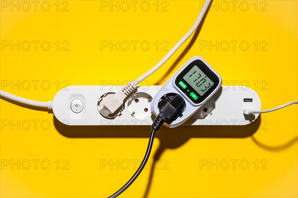 Top view of an energy cost meter in a power strip against a yellow background
