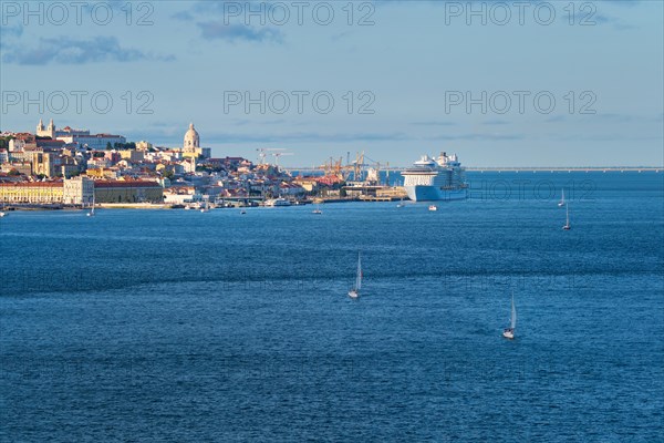 View of Lisbon over Tagus river from Almada with yachts tourist boats and moored cruise liner on sunset. Lisbon