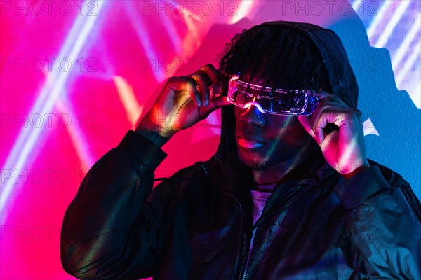 Studio portrait with purple and blue neon lights of an afro futuristic cool man in a metaverse realisty