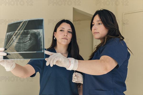 Radio dentist checking x-ray with assistant. Female dentist analyzing x-ray image