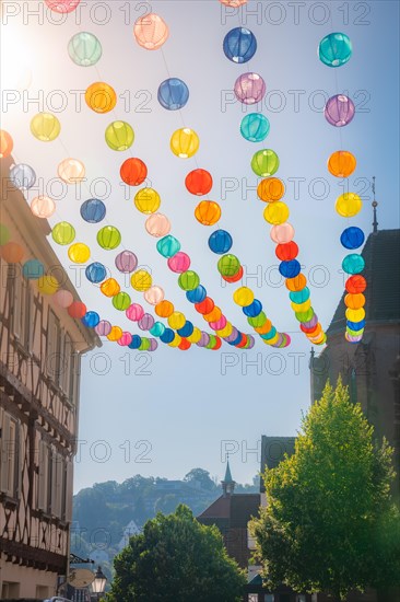 Colourful lanterns hanging in alleyway alley between half-timbered houses