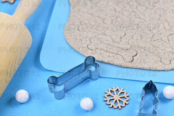 Bone shaped cookie cutter for baking Christmas dog cookies surrounded by raw rolled out dough