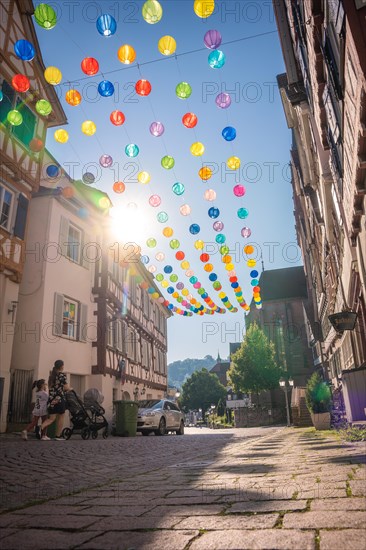 Colourful lanterns hanging in alleyway alley between half-timbered houses