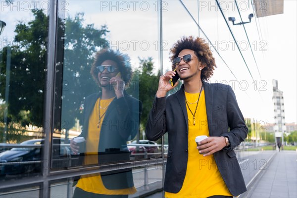 Modern businessman talking to the mobile walking on the street in the morning with a take away coffee