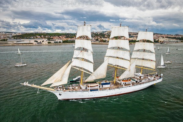 Aerial drone view of tall ships with sails sailing in Tagus river towards the Atlantic ocean in Lisbon