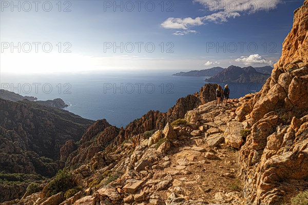 Two woman walking in the Calanche a bizarre rocky landscape on the south coast of the Gulf of Porto in the Regional nature park Park Corsica France Europe