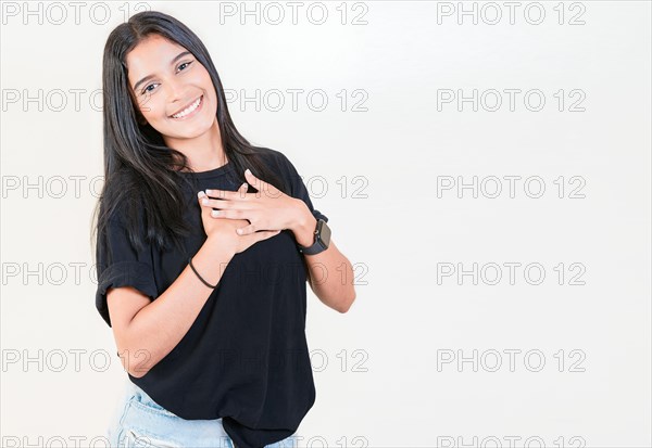 Grateful teenage girl smiling with hands on chest isolated. Positive latin girl with hands on chest. Thankful people with hands on heart