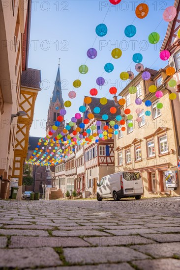 Colourful lanterns hanging in alleyway alley between half-timbered houses