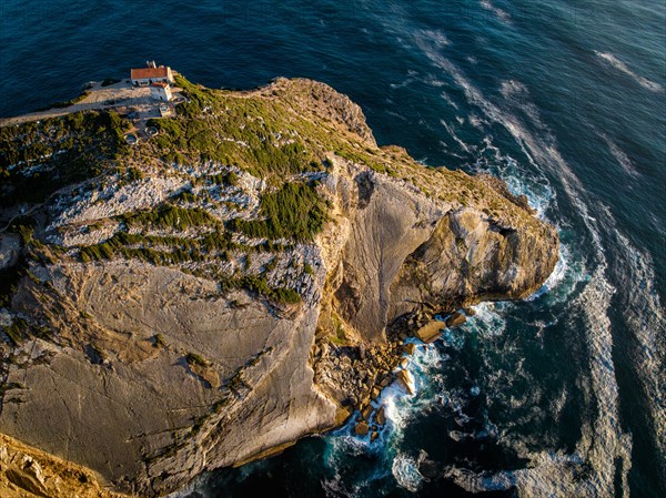 Aerial drone view of Cabo Espichel cape Espichel on Atlantic ocean at sunset with ruins