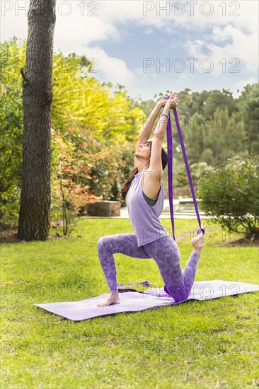 Mid adult female exercising yoga with strap
