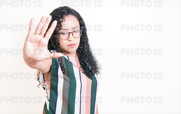 Latin girl gesturing stop with palm of hand isolated. Woman in glasses rejecting with the palm of her hand