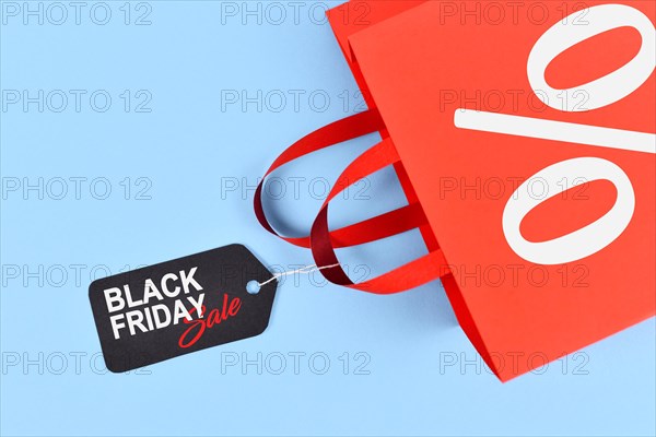 Red shopping bag with tag with Black Friday sale tag on blue background