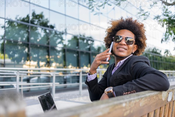 Horizontal photo with copy space of a successful businessman talking to the mobile sitting outdoors