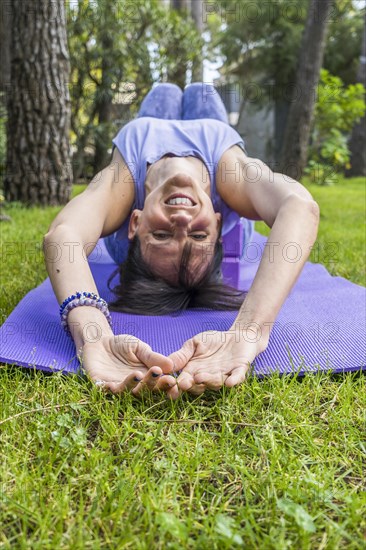Happy smiling woman lying on yoga blocks while looking at camera. Vertical shot