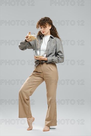 Healthy eating and weight control concept. Young woman pours dry chickpeas from bowl
