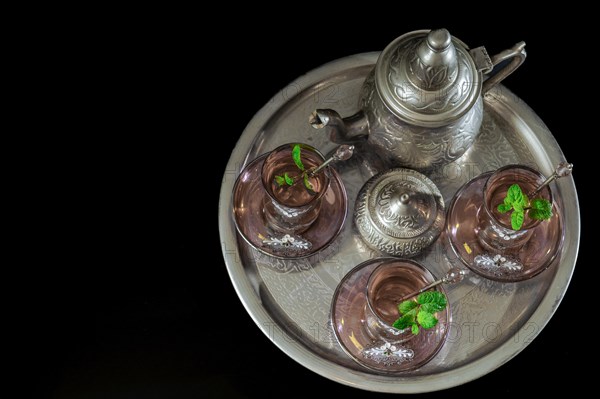 Top view of a traditional Moorish mint tea service on a tray with decorated glassware and silver teapot and sugar bowl