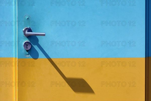 Yellow-cyan iron door with lock and door handle with shadow