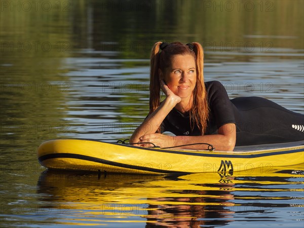 Woman lying relaxed on standup paddle board in lake