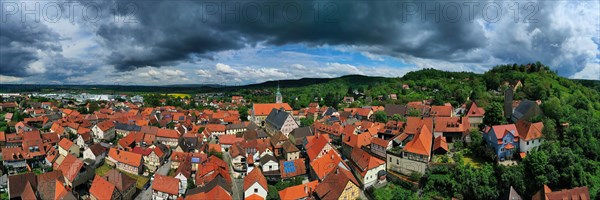 Aerial view of Koenigsberg in Bavaria. The city is surrounded by hills and forests. The sky is cloudy and dark