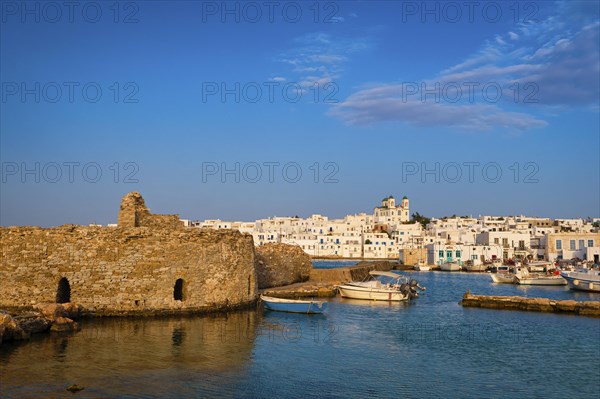 Traditional Greek whitewashed houses and church of Dormition of Mother of God as local landmark on hilltop by seafront on sunny day