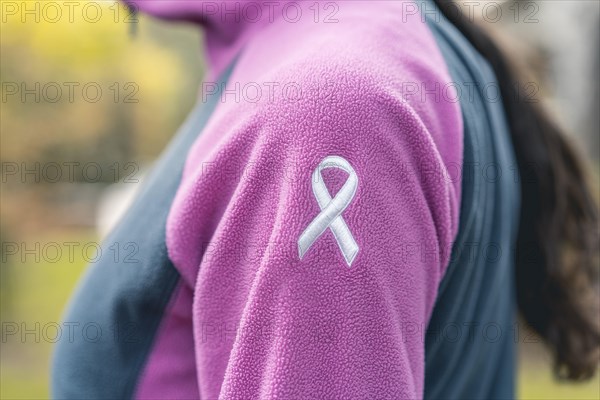 Side view of a woman wearing a sweatshirt with an embroidered cancer awarness ribbon