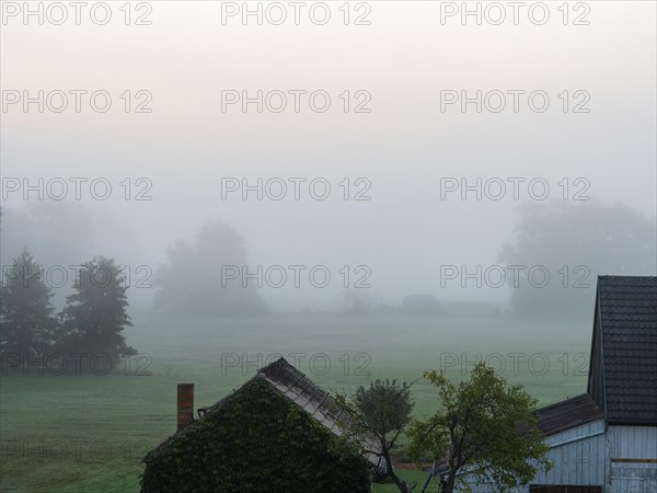 Old farm and landscape in the morning mist in autumn