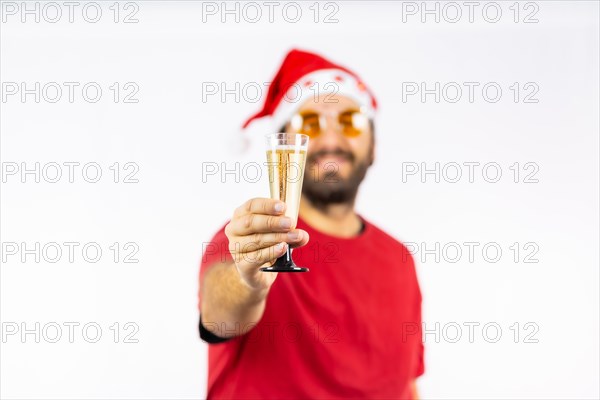 Very happy young Caucasian man with red Christmas hat toasting with a glass of champagne on a white background