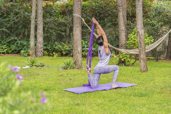 Back view of a woman exercising yoga with strap. Copy space