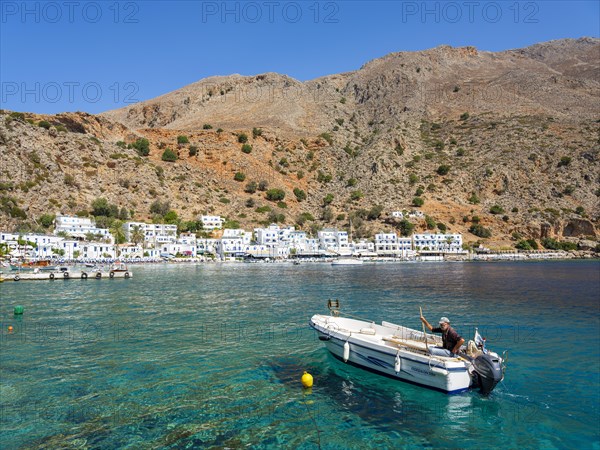 Small fishing boat in the harbour of Loutro below a rocky mountain