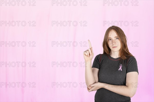 Woman wearing a pink breast cancer awareness ribbon. Concept of struggle with breast cancer