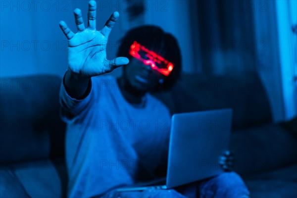 Gamer using augmented reality goggles in a living room with neon blue light