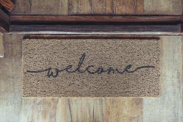 Welcome mat in front of door over wooden floor