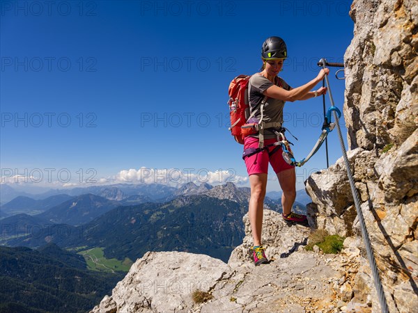 Young woman climbing the south face via ferrata on the Grosser Buchstein