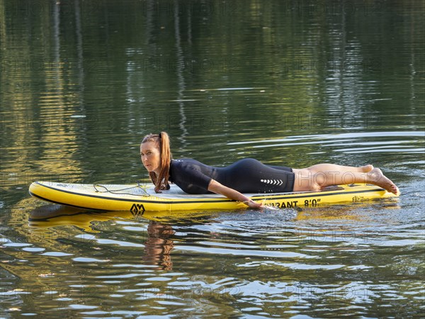 Woman lying relaxed on standup paddle board in lake