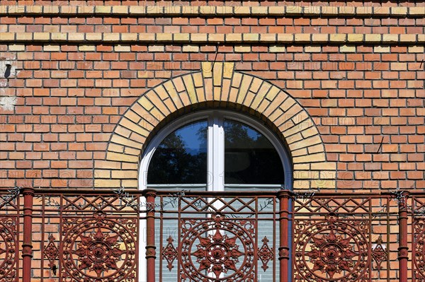 Clinker facade with arched window and richly decorated balcony railing