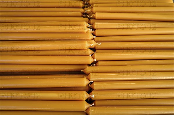 Pile of new yellow wax candles used in churches