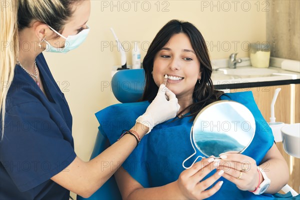 Female dentist checking on female patient teeth color