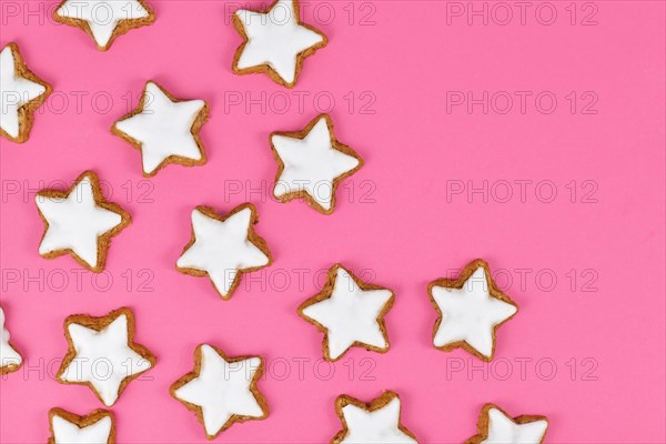 German star shaped glazed cinnamon Christmas cookies called 'Zimtsterne' on pink background