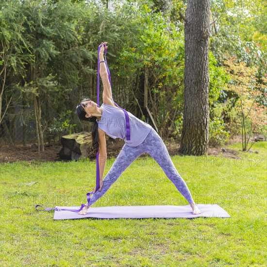 Portrait of sporty woman in sportswear working out with strap outdoor