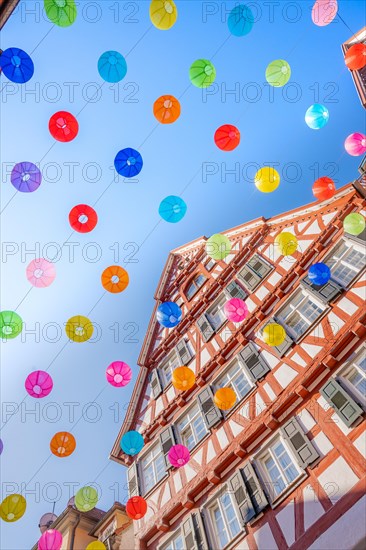 Colourful lanterns hanging in alleyway alley between half-timbered houses