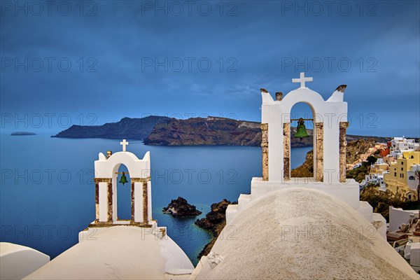 Two bell towers and dome roofs of white Greek Orthodox church in Oia village