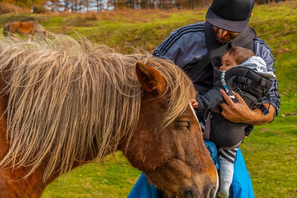 A father and his baby caress a wild horse on Mount Erlaitz in the town of Irun