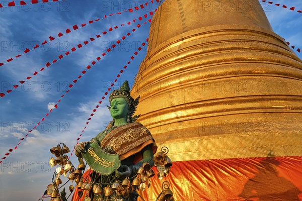 Statue of green-skinned Thai angel holding roll with message in Thai