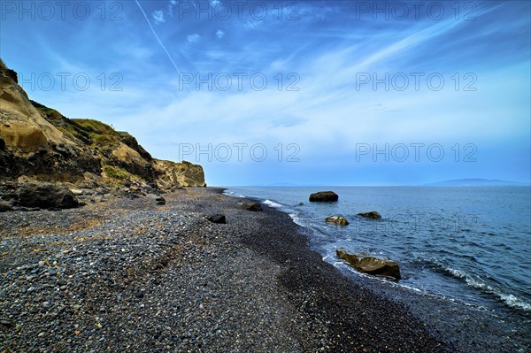 Dramatic landscape of blue sea or ocean waves rolling on rocky volcanic beach on cloudy day. Blue sky