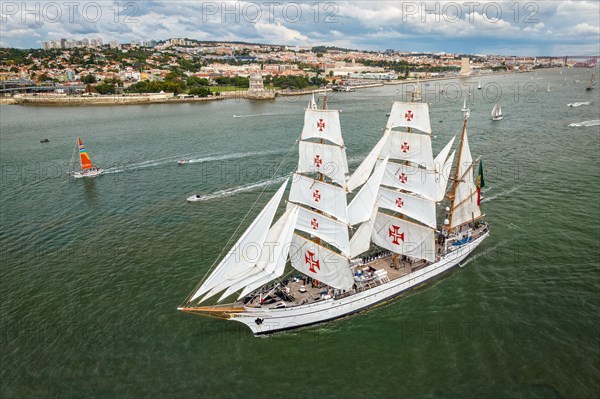 Aerial drone view of tall ships with sails sailing in Tagus river towards the Atlantic ocean in Lisbon