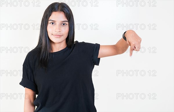 Cheerful girl pointing advertising down. Smiling latin girl pointing down an advertisement. Latin people pointing down at a banner