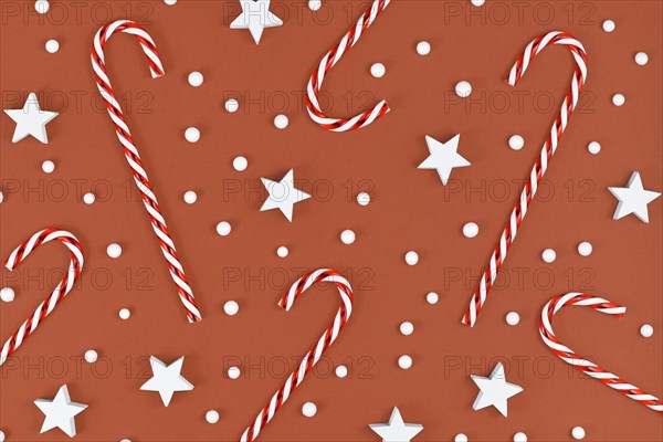 Christmas flat lay with candy canes and star and snow ornaments on brown background