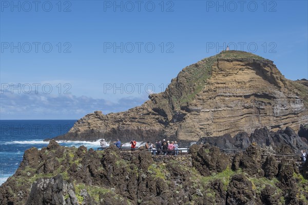 Tourists look from viewing platform at natural lava pools for bathing